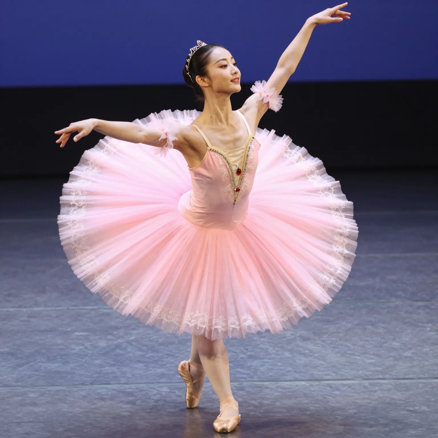A woman gracefully performing on stage in a pink tutu dress, highlighting its elegance and design.